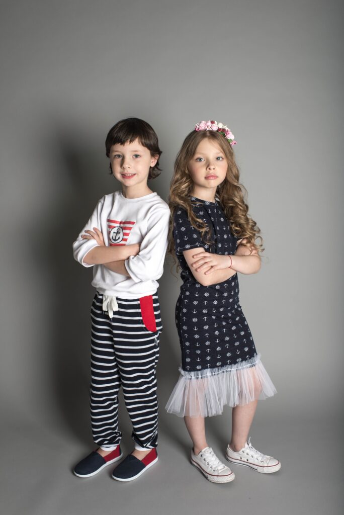Two adorable children standing side by side, arms crossed, posing for a photoshoot.