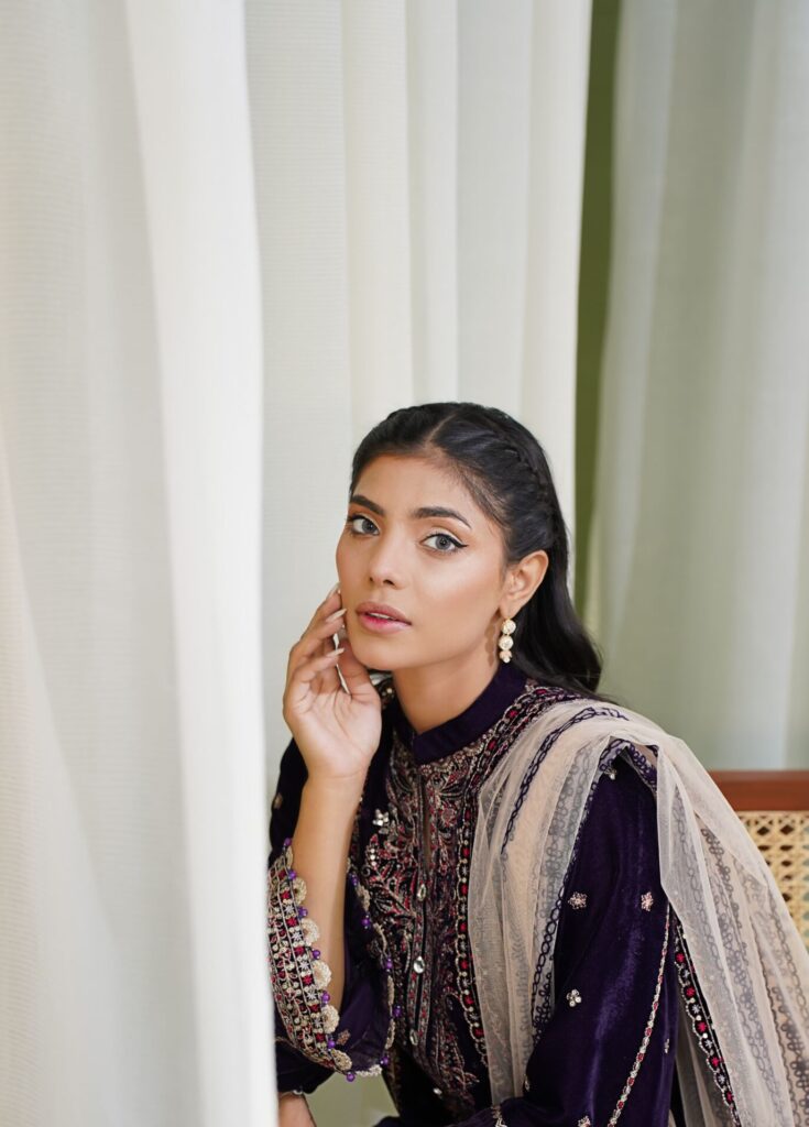 Young woman in a stunning traditional Pakistani outfit posing elegantly indoors.