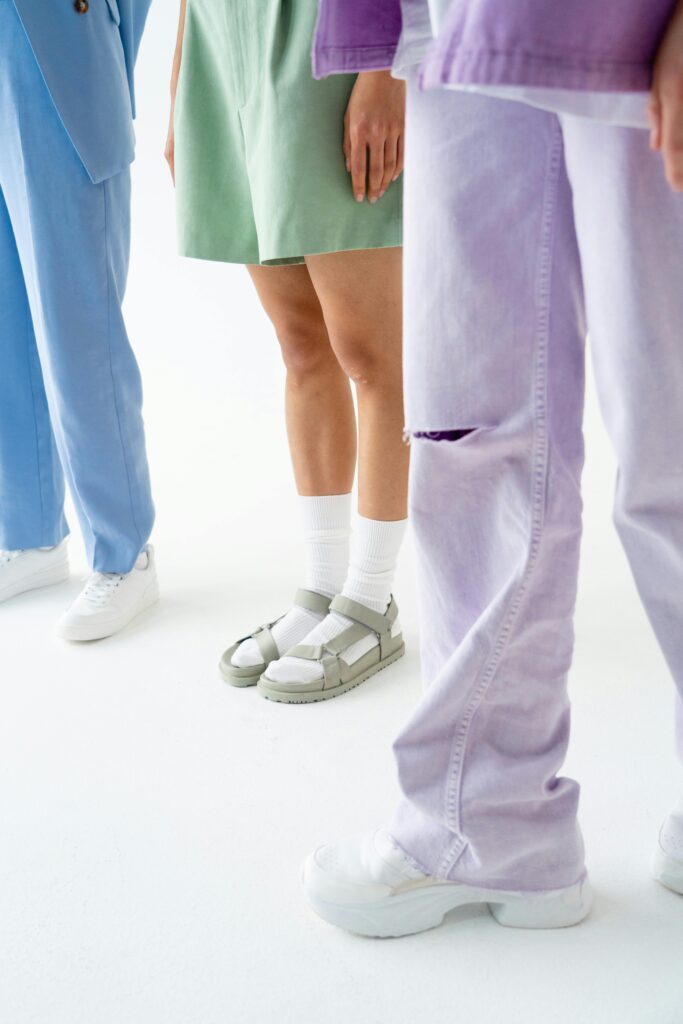 Stylish trio showcasing pastel fashion with white sneakers and sandals.