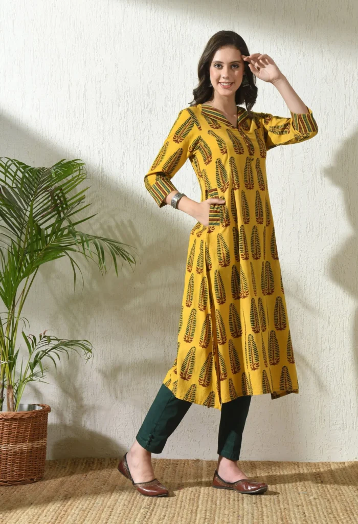 Woman posing in stylish Ajrakh printed cotton kurta, showcasing ethnic fashion indoors.