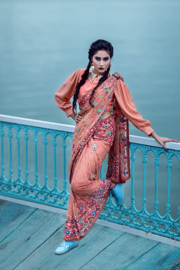 Elegant Indian woman posing on a dock in a vibrant traditional sari and modern blouse.